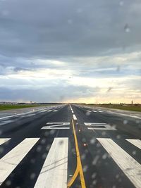 View of airport runway against cloudy sky