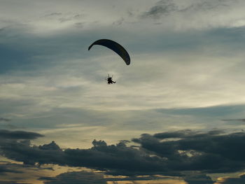 Low angle view of woman paragliding against sky