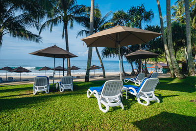 Deck chairs on beach against sky