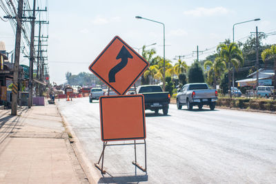 Road sign on street in city against sky