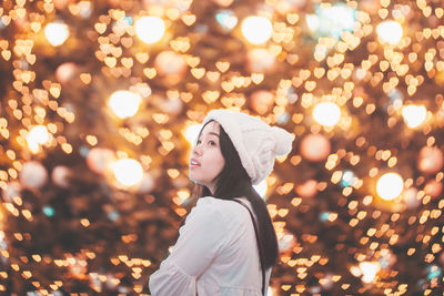 Close-up of young woman against illuminated lights