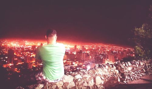 Rear view of woman against illuminated cityscape at night