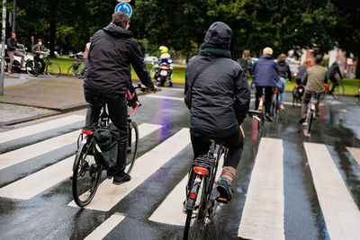 Rear view of people riding bicycle on road