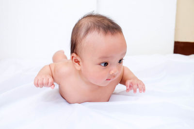 Close-up of baby girl lying on bed