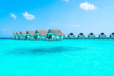 Houses by swimming pool by sea against blue sky