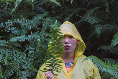 Portrait of woman in raincoat standing against plants