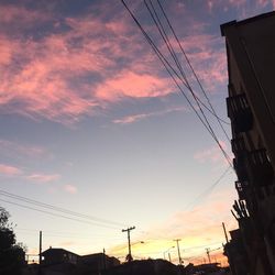 Low angle view of silhouette electricity pylon against sky during sunset