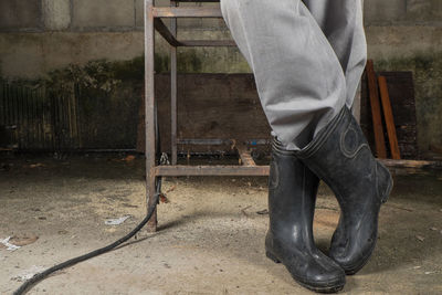 Low section of man wearing rubber boots in workshop