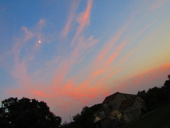 Low angle view of silhouette trees against dramatic sky