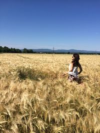 Rear view of woman standing on grassy field against clear sky