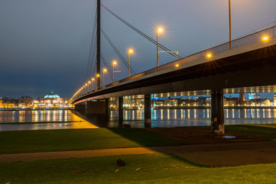 Illuminated bridge over street against sky at night