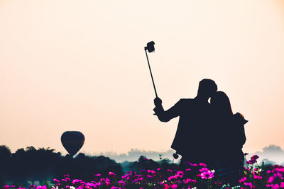 Silhouette couple taking selfie against clear sky