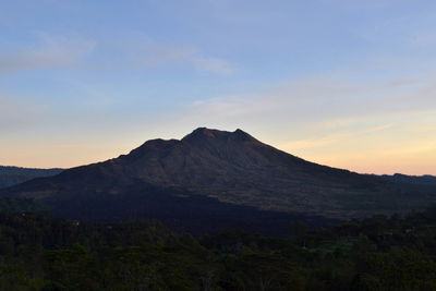 Scenic view of volcanic mountain against sky during sunset