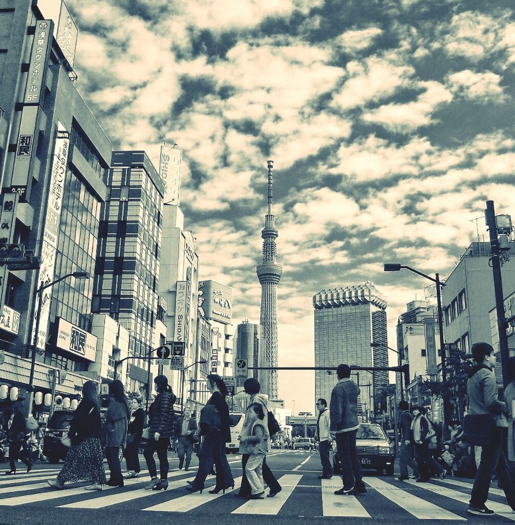 architecture, built structure, building exterior, city, large group of people, sky, men, person, city life, street, walking, cloud - sky, lifestyles, cloud, building, leisure activity, day, city street, road