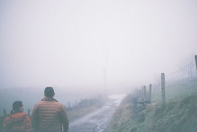 Rear view of people on road against sky during winter