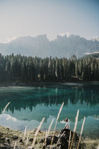 Man sitting on rock at carezza lake in south tyrol, italy