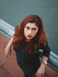 High angle portrait of woman leaning on railing at observation point against sea