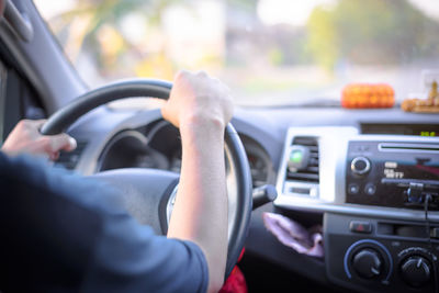 Low section of man driving car on road