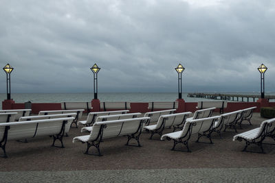 Chairs and tables on beach against sky