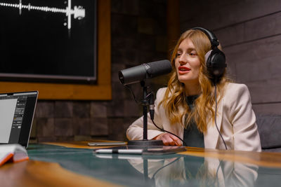 Cheerful young woman recording podcast in studio with copy space