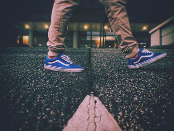 Low section of man standing on illuminated street at night