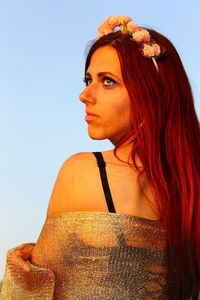 Close-up portrait of young woman against clear sky