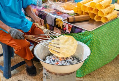 The old woman grilled crackers on charcoal, old thai crackers in street food market.