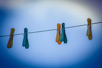 Low angle view of clothespins hanging on clothesline against sky