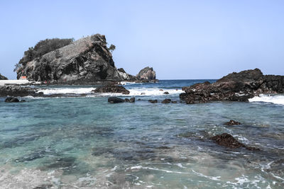 Scenic view of rock formation in sea against clear sky