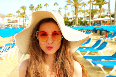 Portrait of young woman wearing sunglasses and hat at beach