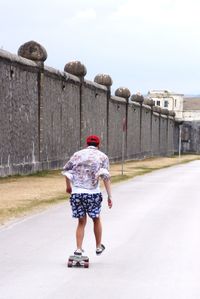 Rear view of man roller skating on road