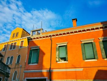 Low angle view of yellow building against blue sky