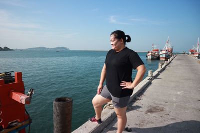 Woman looking away standing on pier over sea