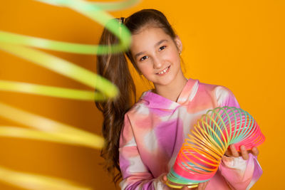 Portrait of young woman standing against yellow background