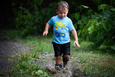 Full length of boy playing in rain