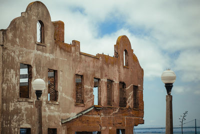 Low angle view of ruin against cloudy sky