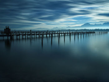 Wooden posts in lake against sky