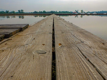 Surface level of wooden pier over lake against sky