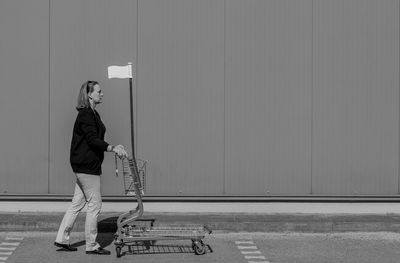 Woman with shopping cart against wall
