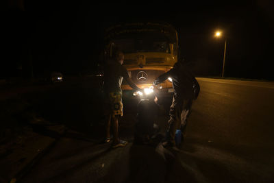 People on illuminated road at night