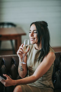 Woman with mobile phone sitting on sofa at home