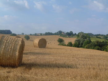 Hay bales on field against sky