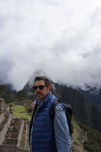 Man standing by machu picchu against cloudy sky