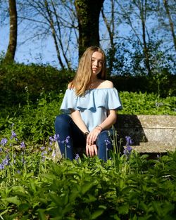 Beautiful young woman sitting on seat amidst plants