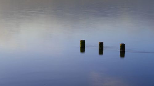 Close-up of wooden post in lake against sky