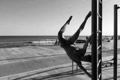 Man performing stunt at beach against sky