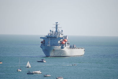 Boats with ship sailing in sea against sky