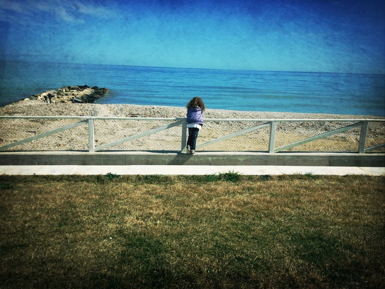 sea, rear view, horizon over water, standing, water, full length, lifestyles, leisure activity, railing, sky, tranquil scene, blue, tranquility, walking, person, nature, beauty in nature, scenics