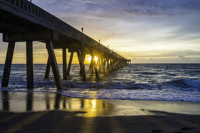 Pier over sea against sky during sunset