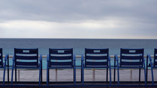Lounge chairs on beach against sky